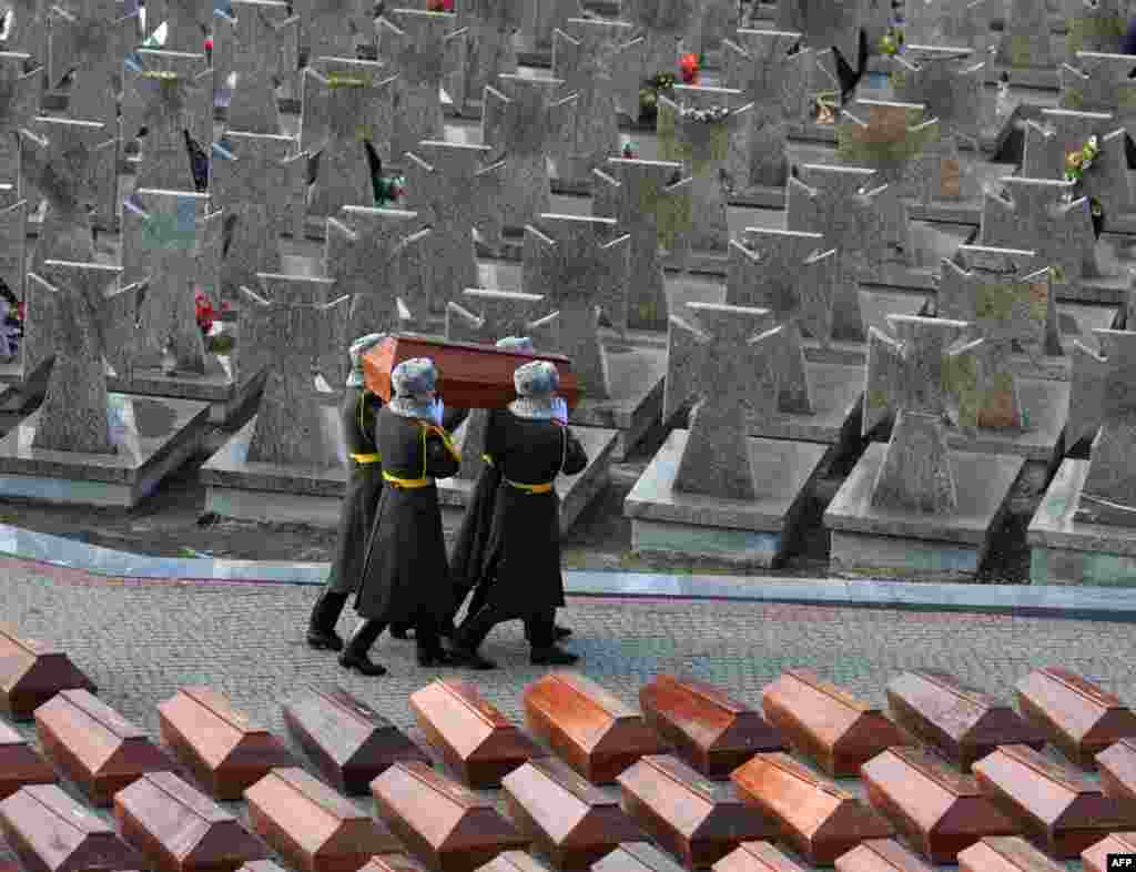 An honor guard carry coffins with human remains during a reburial ceremony in Lviv, Ukraine. The remains of more than 500 apparent victims of the Soviet regime were reburied on February 3 at a cemetery in the western Ukrainian city. The bones of 511 people -- 67 of them children -- were found in two separate locations by construction workers and residents in 2014-2015. (AFP/Yuriy Dyachyshyn)