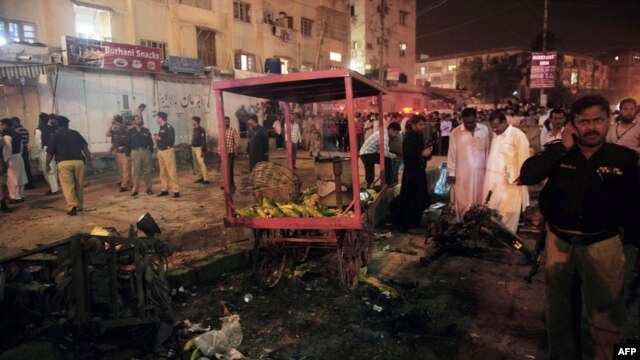 Pakistani security officials scan the site of a bomb blast at a Karachi, which killed at least six people on September 18.