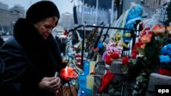 A woman lights a candle as she visits a temporary memorial for Maidan activists or 'Heroes of the Heavenly Hundred', who were killed on Kyiv's Independence Square during antigovernment protests last year.