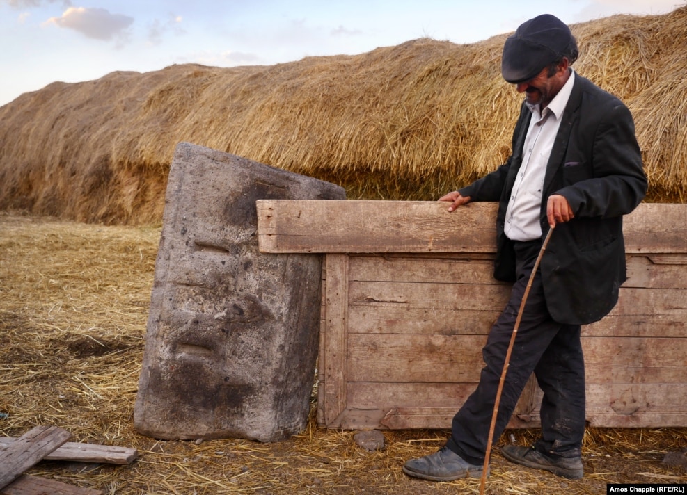 A local from the village of Oguzlu shows a khachkar that is being used as part of a fencepost. The men of the village say they found two khachkars when excavating the foundations of a house in the village.
