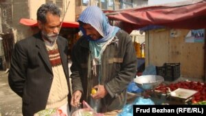 Mohammad Ahmadi (left) speaks to Ghulam, a local vegetable seller, at a campaign rally for Zalmai Rasul in Kabul on March 29.