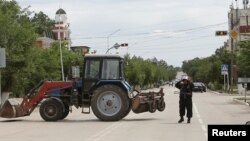 Сотрудник сил безопасности в городе Актобе блокирует движение автомашин. 10 июня 2016 года.