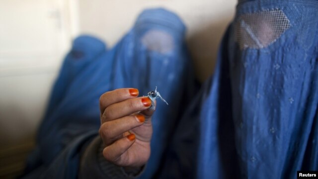 A woman holds up opium as she attends a counseling session at the Nejat drug rehabilitation center in Kabul.