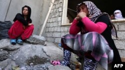 Iraqi Yazidi women who fled the violence in the northern Iraqi town of Sinjar sit outside a school, where they are taking shelter in the Kurdish city of Dohuk in Iraq's autonomous Kurdistan region, on August 5.