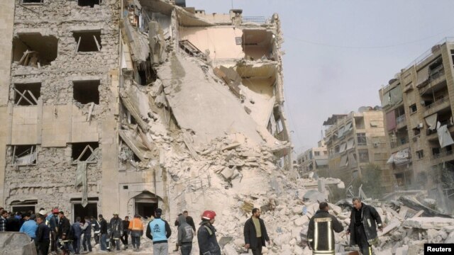 Security personnel and civilians gather at the site of a large blast in a neighborhood of Aleppo on January 18. State television blamed the explosion on "terrorists," a term used to describe antigovernment rebels.