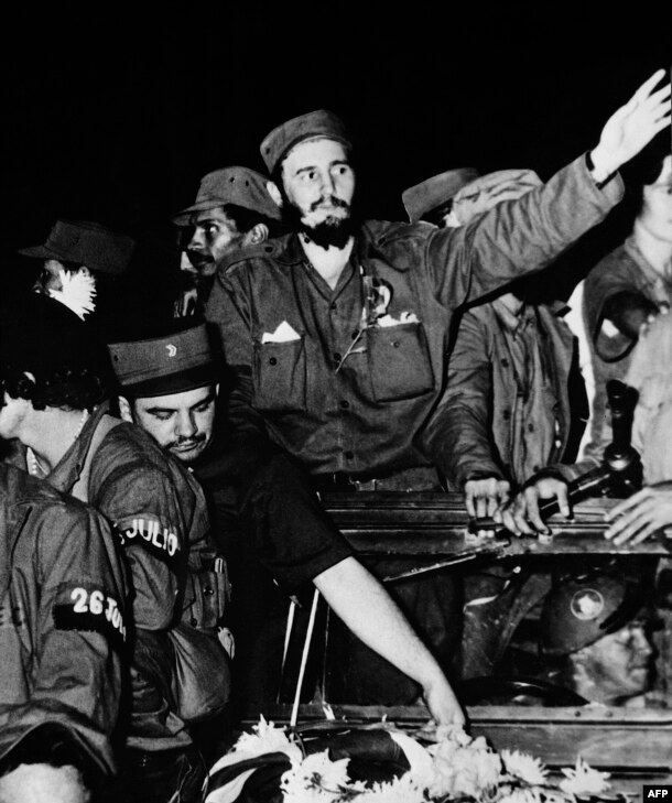 Surrounded by members of his leftist guerrilla movement, Castro (center) waves to crowds in Cienfuegos shortly after ousting Cuban dictator Fulgencio Batista in 1959. 