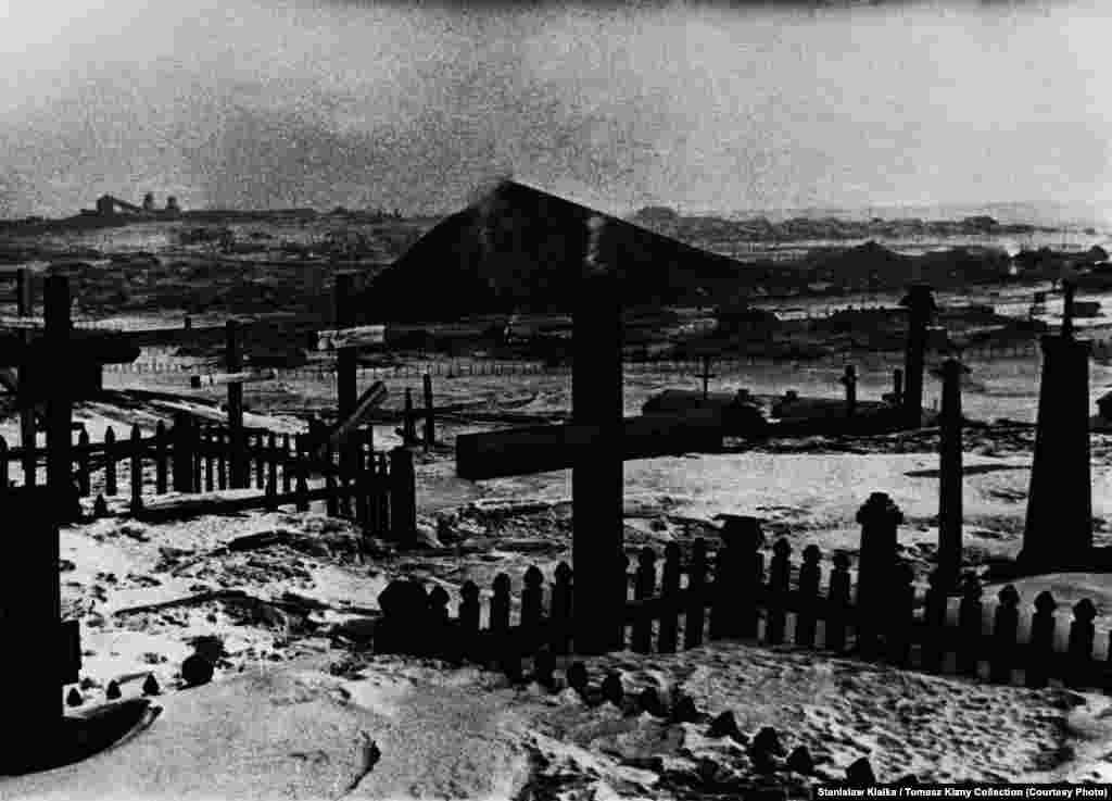 An undated photo showing a cemetery for prisoners and exiles with mines visible in the background. Prisoners were buried in the tundra and their grave was marked with a post bearing the dead person's camp number. After 1956, released prisoners identified the graves and placed crosses marked with their names.