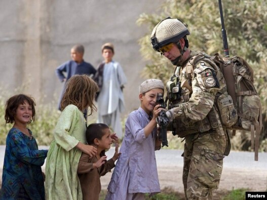 A British Army Major shows his rifle to Afghan children during a patrol near Lashkar Gah, the capital of Helmand Province.