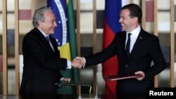 Brazilian Vice President Michel Temer (left) and Russian Prime Minister Dmitry Medvedev exchange documents during a signing ceremony in Brasilia on February 20.