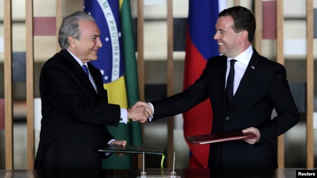 Brazilian Vice President Michel Temer (left) and Russian Prime Minister Dmitry Medvedev exchange documents during a signing ceremony in Brasilia on February 20.