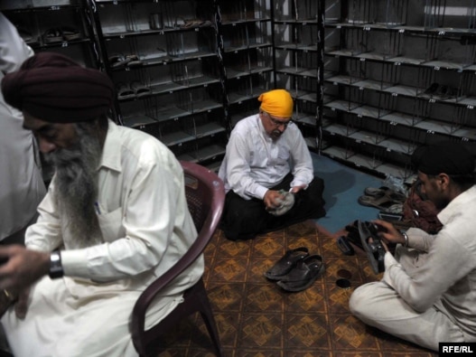 Khurshid Khan (in yellow head-covering) shining shoes to help show  brotherhood with the Sikh community in Peshawar.