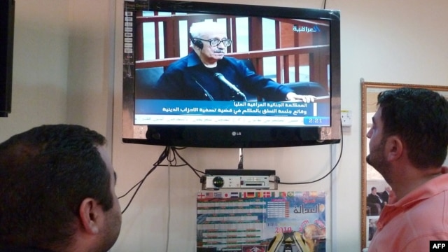Iraqis watch a state television broadcast in Baghdad in 2010.