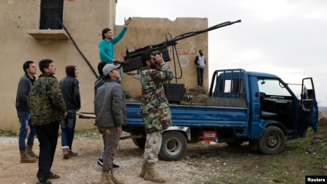 A rebel fighter from the Ahrar al-Sham Islamist movement gestures while standing on a pick-up truck mounted with an antiaircraft weapon, as he looks at the sky with his fellow fighters outside Idlib.