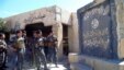 Iraqi policemen stand in front of a a flag belonging to the Islamic State (IS) group painted on a wall in a town outside Tikrit on March 8, where Iraqi continue their assault. 