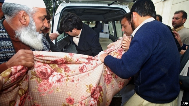 Policemen shift the dead body of Kamran Faisal, who was investigating a corruption scandal involving Prime Minister Raja Pervez Ashraf and was found dead in a government hostel in Islamabad on January 18.
