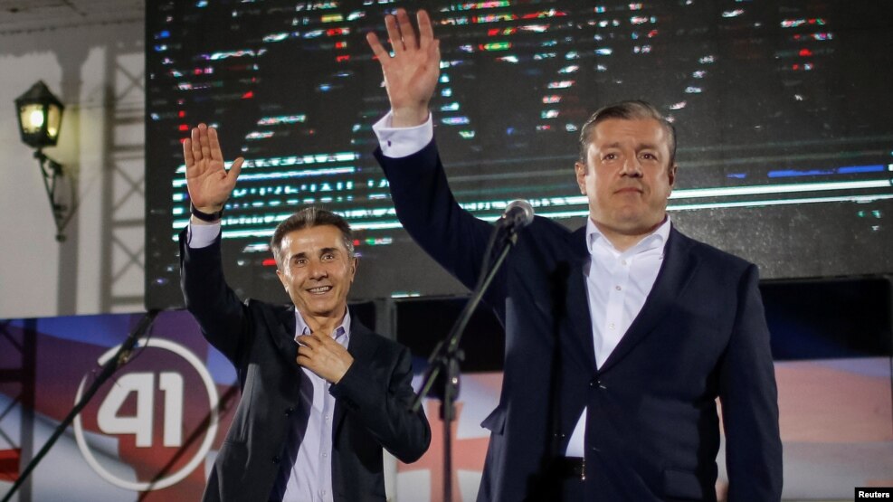 Bidzina Ivanishvili (left) and Prime Minister Giorgi Kvirikashvili wave at a Georgian Dream rally after the first round of the parliamentary elections in Tbilisi on October 8.
