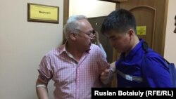 Председатель Союза журналистов Казахстана Сейтказы Матаев (слева) в сопровождении медика в здании суда. Астана, 23 августа 2016 года.