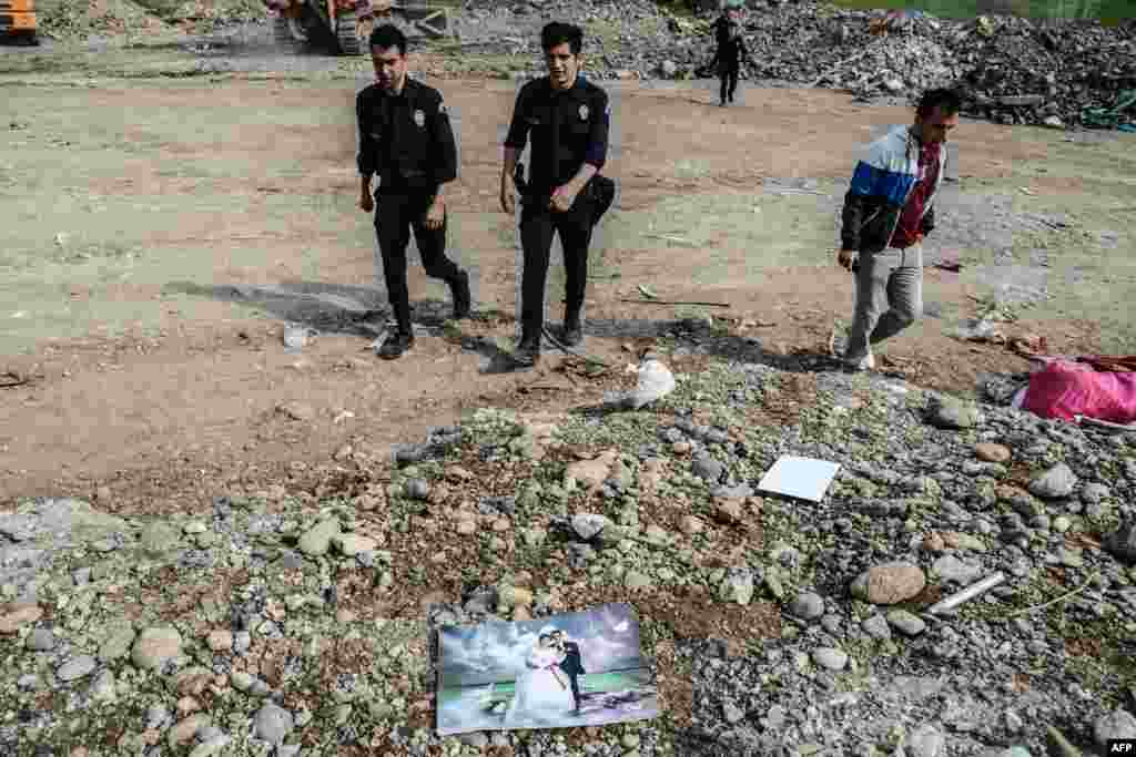 Turkish police officers walk past a wedding photograph in a dump in Diyarbakir in southeastern Turkey. Rubble from destroyed homes has been dumped at this site following months of clashes between Kurdish militants and Turkish government forces in Sur district. (AFP/Ilyas Akengin)
