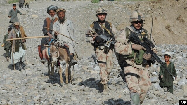 NATO-led International Security Assistance Force (ISAF) soldiers walk with villagers during a search for victims following an earthquake in Baghlan Province in June.