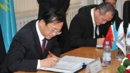 Sinopec Engineering компаниясының бас директоры Чжу Хайсин (сол жақта) және Атырау мұнай өңдеу заводының бас директоры Талғат Байтазиев шарт жасасып отыр. Атырау, 29 қазан 2009 жыл.