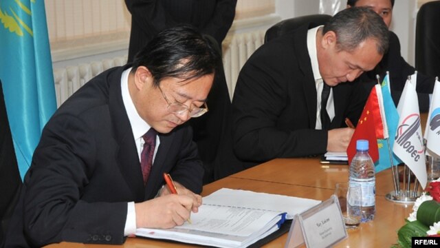 Sinopec Engineering компаниясының бас директоры Чжу Хайсин (сол жақта) және Атырау мұнай өңдеу заводының бас директоры Талғат Байтазиев шарт жасасып отыр. Атырау, 29 қазан 2009 жыл.