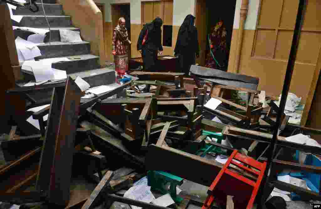 Teachers inspect the wreckage of a burned-out school in Lahore on November 3 after it was set on fire by an angry mob alleging that the school gave a test that insulted the Prophet Mohammed.
