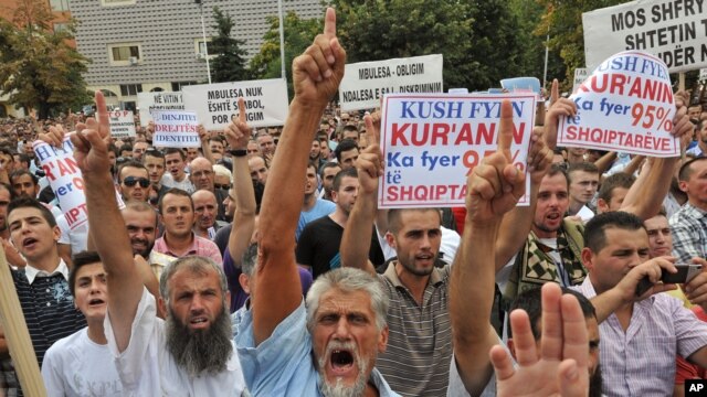 Muslim protesters hold banners reading " Dignity, Justice, Identity" in Pristina