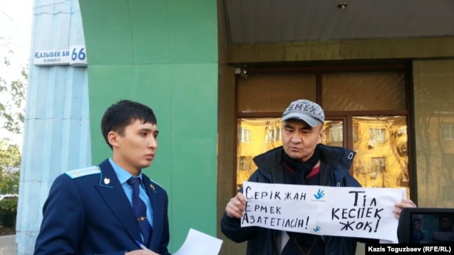 Гражданский активист Макс Бокаев (справа) проводит пикет в поддержку активистов Серикжана Мамбеталина и Ермека Нарымбаева, арестованных по обвинению в "разжигании розни". Алматы, 26 октября 2015 года.