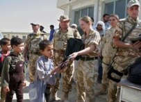 British and Romanian soldiers hand out bookbags to students near Kabul on June 30 (epa)