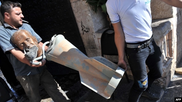 Rebel fighters carry the head of a statue of late President Hafez al-Assad, with a shoe glued to his mouth, along with what appears to be a cluster bomb, which they accuse government forces of using in attacks on rebel-held areas.