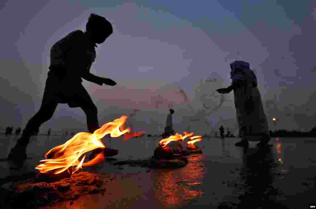 An Indian boy picks up coins offered by devotees during prayers on the bank of the Bay of Bengal as pilgrims arrive for the Gangasagar Fair at Sagar Island, in eastern India, on January 12. (epa/Piyal Adhikary)