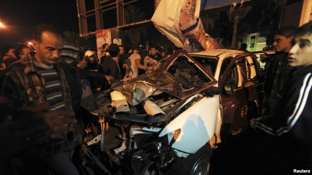 People look at the wreckage of a police car after an attack in Benghazi on January 14. At least one police officer was wounded when attackers threw a hand grenade at the patrol car in a series of assaults on security officials.
