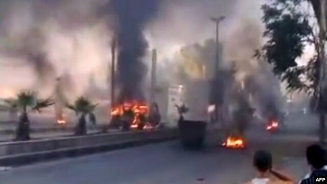 A video grab shows smoke billowing from burning tires and trash containers in the Al-Hajar Al-Aswad district of Damascus on July 18.