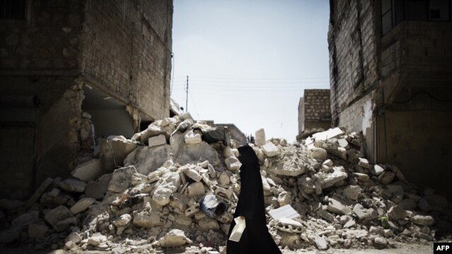 A Syrian woman walks past a destroyed building while reaching a food distribution centre in Aleppo earlier this month. 