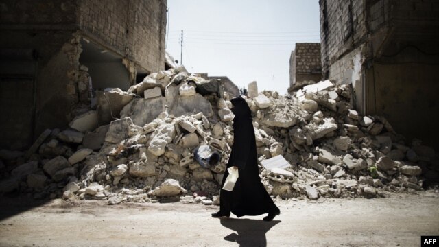 A Syrian woman walks past a destroyed building while walking to a food-distribution center in Aleppo.