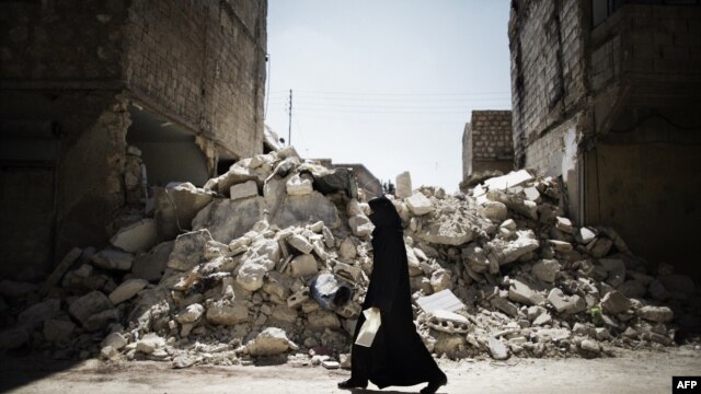 Syria -- A Syrian woman walks past a destroyed building while reaching a food distribution centre in Aleppo on 13Sep2012