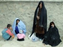 Afghan women and their children wait outside the main hospital in the western Afghan city of Farah earlier this year (AFP)