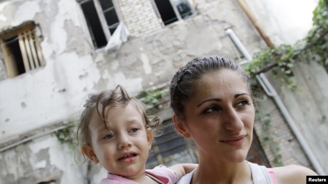 A woman carrying her child stands in front of a state-owned house given to refugees in Tbilisi. (file photo)