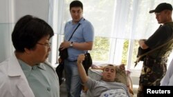 Interim Kyrgyz leader Roza Otunbaeva (left) talks to a patient wounded during ethnic clashes as she visits a hospital in Jalal-Abad today.