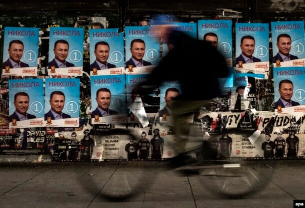 A man rides his bicycle past election posters featuring former prime minister and the leader of the ruling VMRO-DPMNE party, Nikola Gruevski, in Skopje.