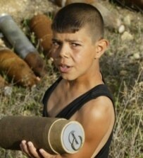A Lebanese boy holds an unexploded cluster bomb, one of many fired by Israeli forces during the war in Lebanon this summer (AFP)