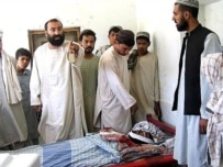 Afghans on June 19 in Kandahar stand near the body of relative they say was killed by foreign troops (AFP)