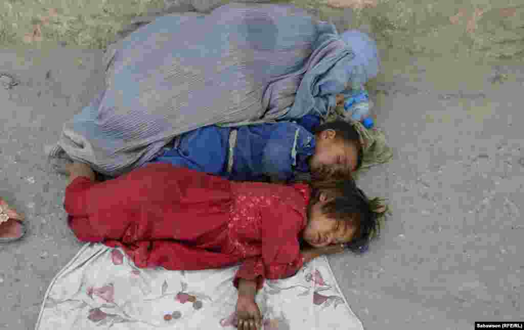An Afghan woman begs with her children beside a road in Kabul on May 31, the day before International Children's Day. (RFE/RL/Sabawoon)