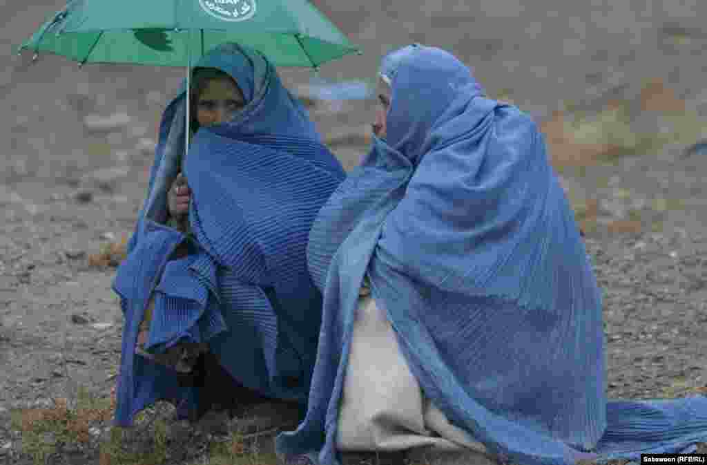 Rain is no deterrent for women waiting to pick up rations.
