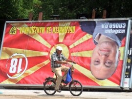 A man rides his bicycle past an upside-down billboard of opposition leader Ljube Boskovski in downtown Skopje