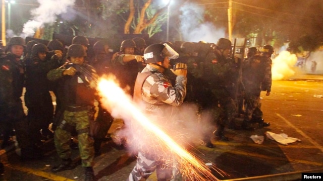 A riot policeman fires his weapon while confronting stone-throwing demonstrators during an antigovernment protest in Belem, Brazil, at the mouth of the Amazon River, on June 20.