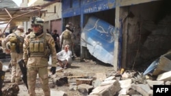 Iraqi security forces inspect the damage following a car bomb in the Aziziyah, south of Baghdad, on April 16.