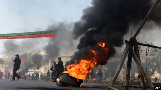 Activists of Imran Khan's Pakistan Tehrik-e Insaaf (PTI) party block a road with burning tires during an antigovernment protest in Lahore on December 15.