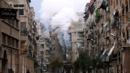 A man stands in an empty street near a burning building hit by a mortar shell fired by Syrian Army soldiers, in the Zamalka neighborhood of Damascus.
