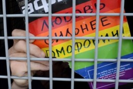 Шеру кезінде полиция тұтқындаған гей-белсенді "Гомофобиядан махаббат күшті!" деген жазуды полиция көлігінен көрсетіп тұр. Мәскеу, 25 мамыр 2013 жыл.